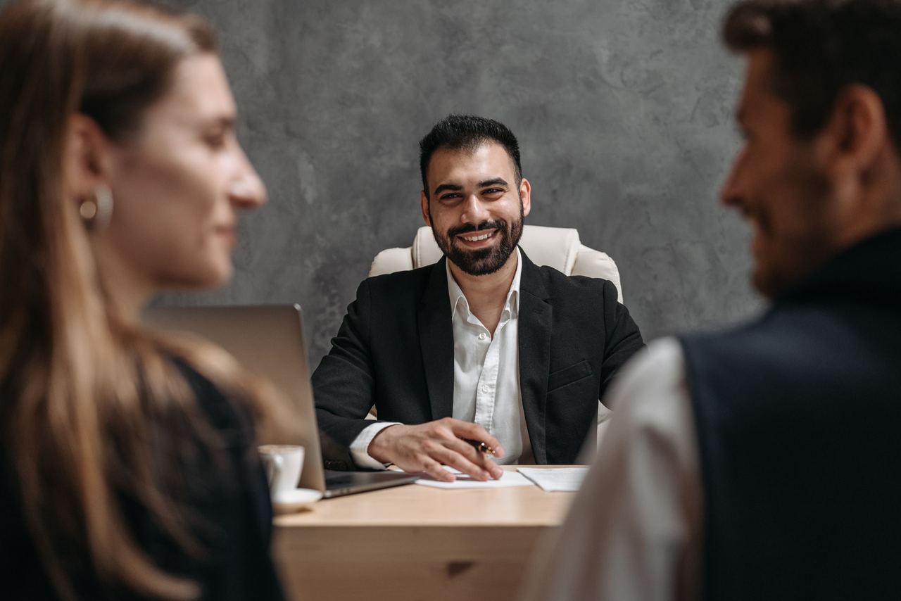 A manager smiling with approval across a meeting table